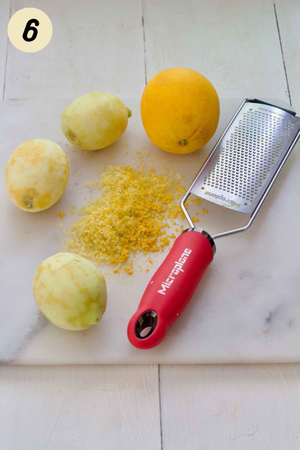 Zested lemons and an orange on a board with fine grater.