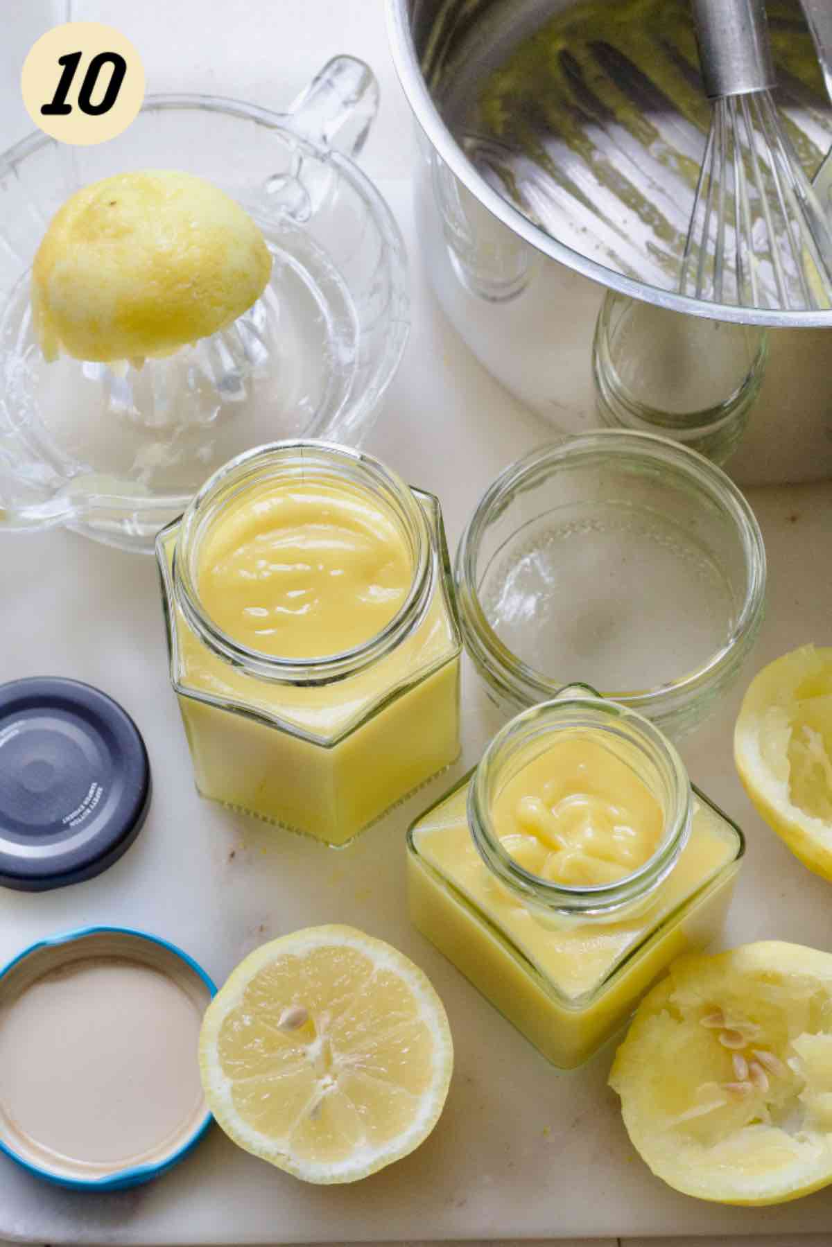 Two jars filled with curd, lemons, empty pan, jar lids.