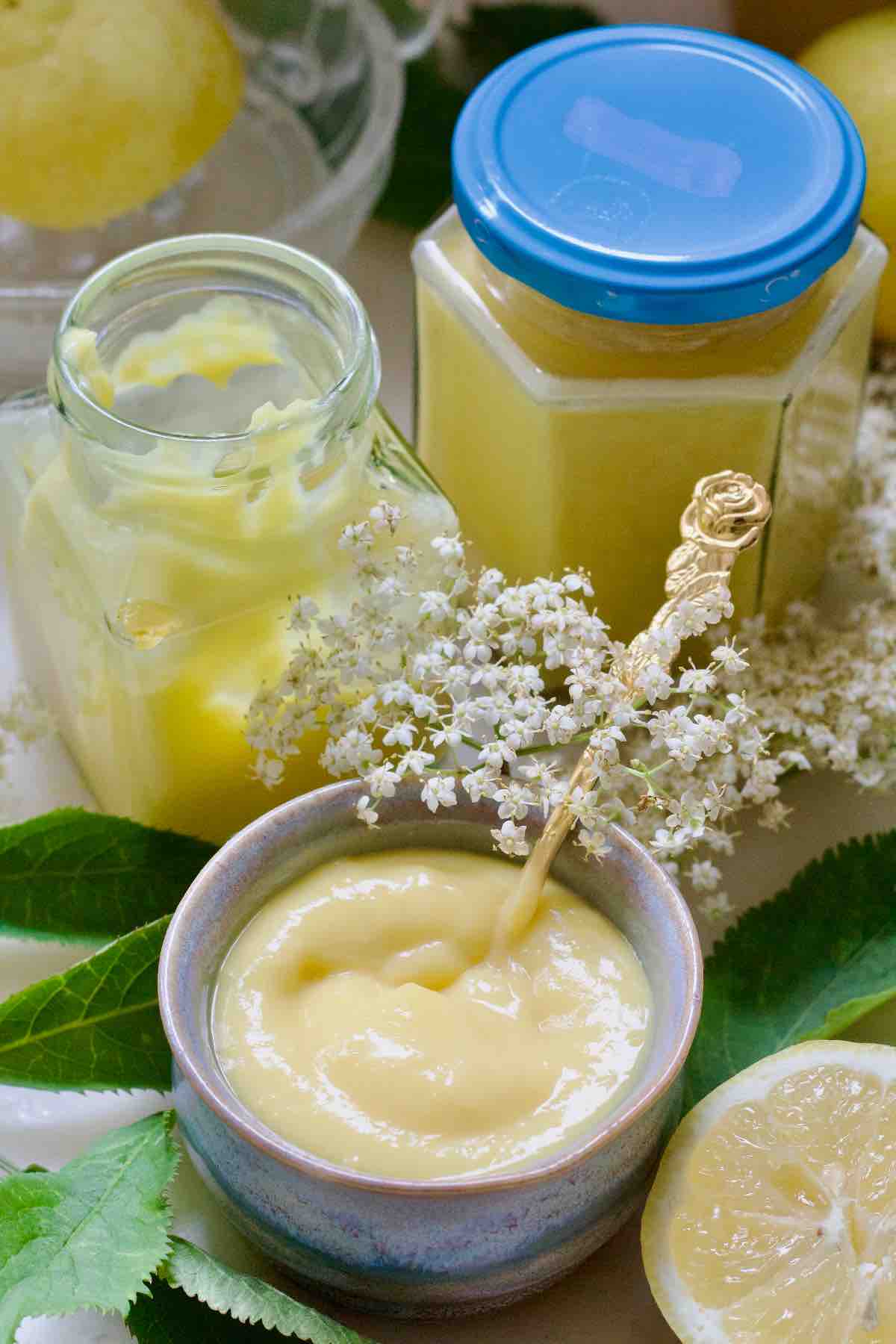 Bowl with curd, fresh elderflowers and two jars.