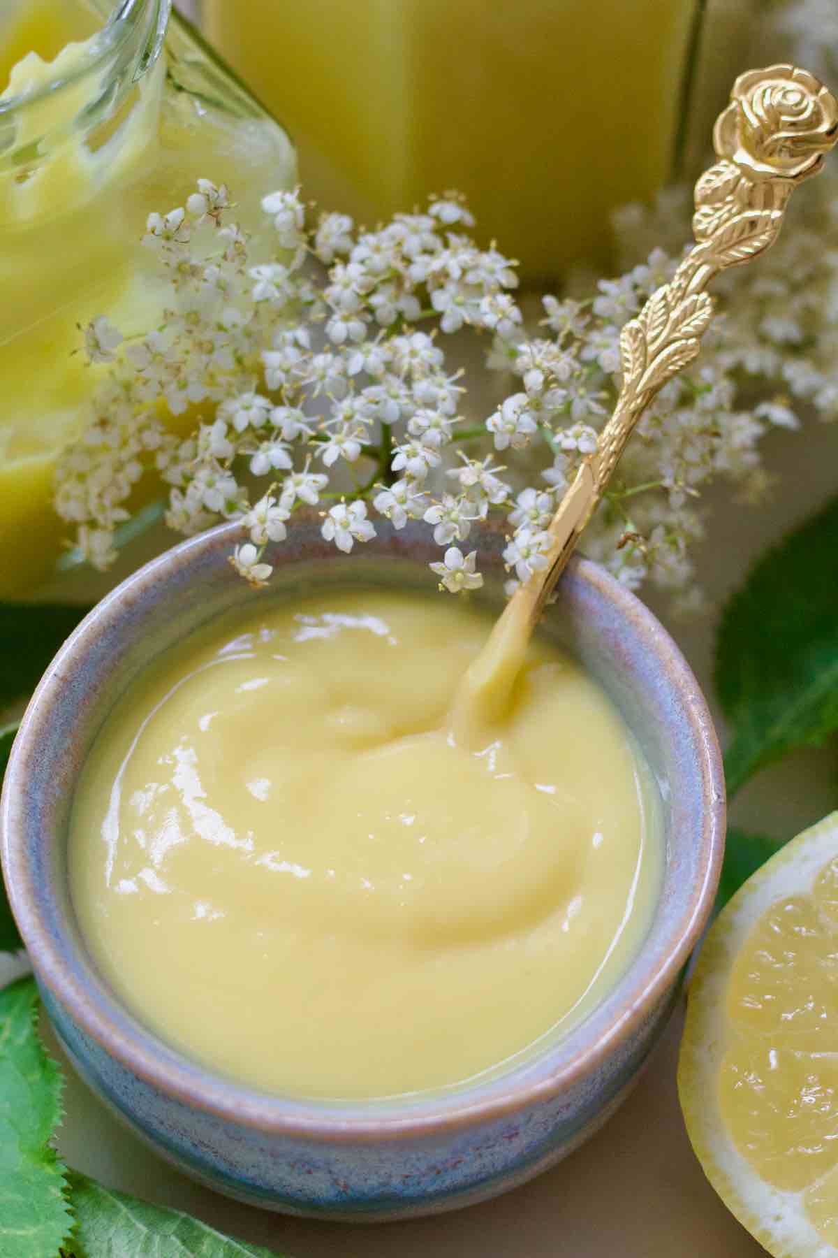 Small bowl of freshly made elderflower curd, fresh elderflowers.