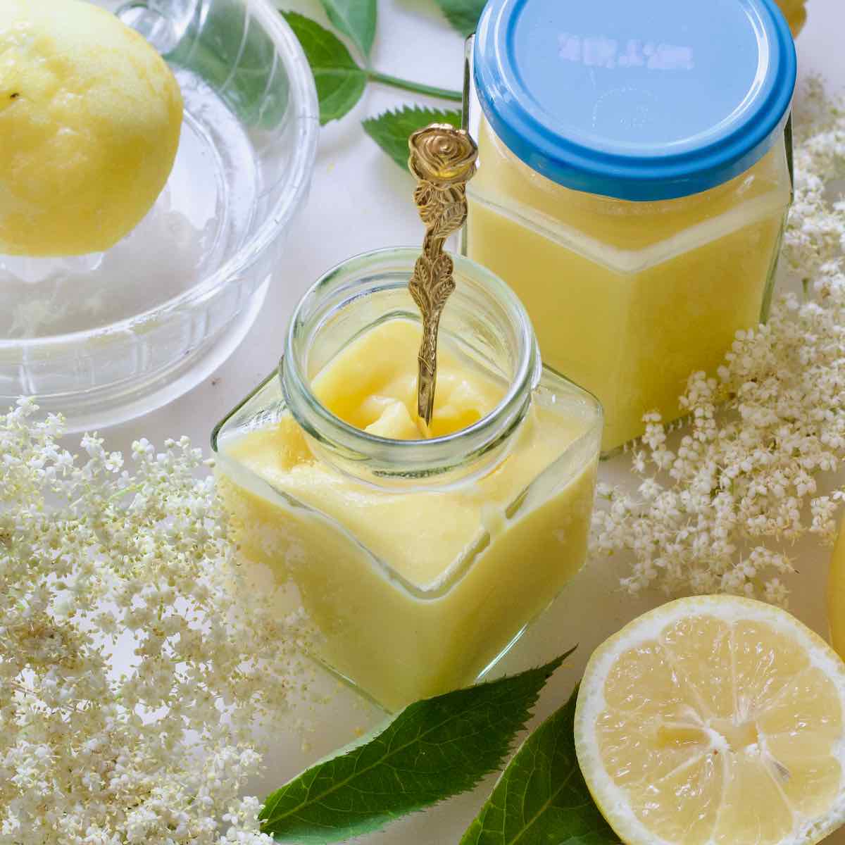 Small open jar of elderflower curd with a spoon.