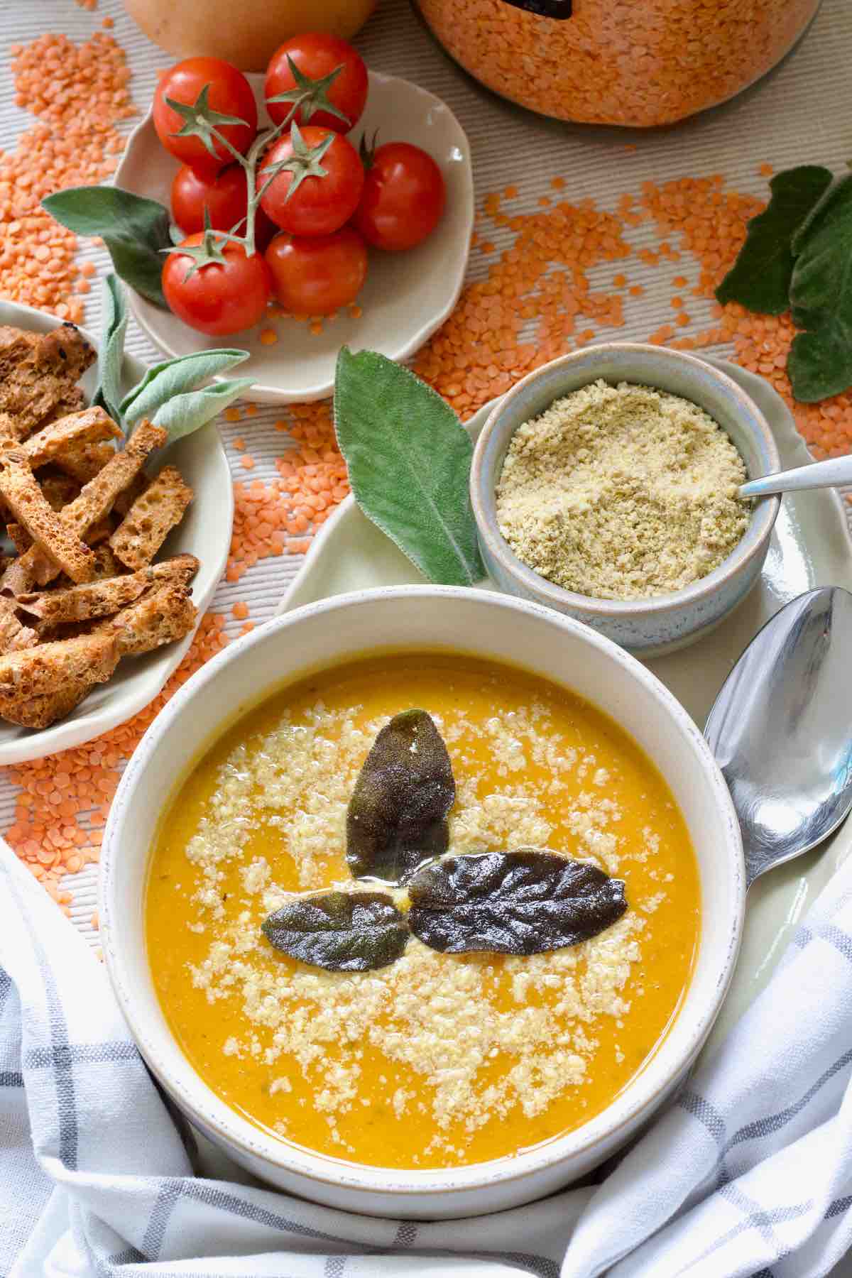 Bowl of soup on a tray with a spoon and bowl full of parmesan.