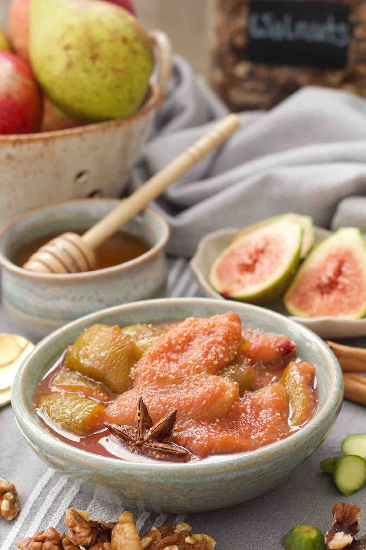 Fig compote in a bowl with fresh figs and honey in the background.