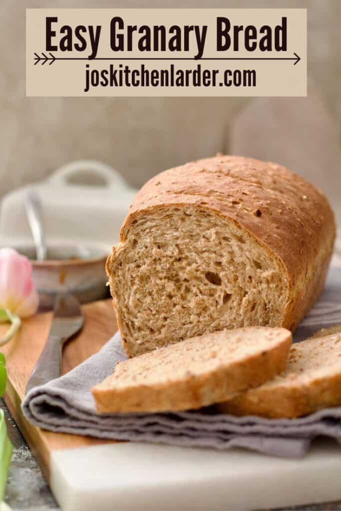Granary bread loaf with two slices cut in front of it.