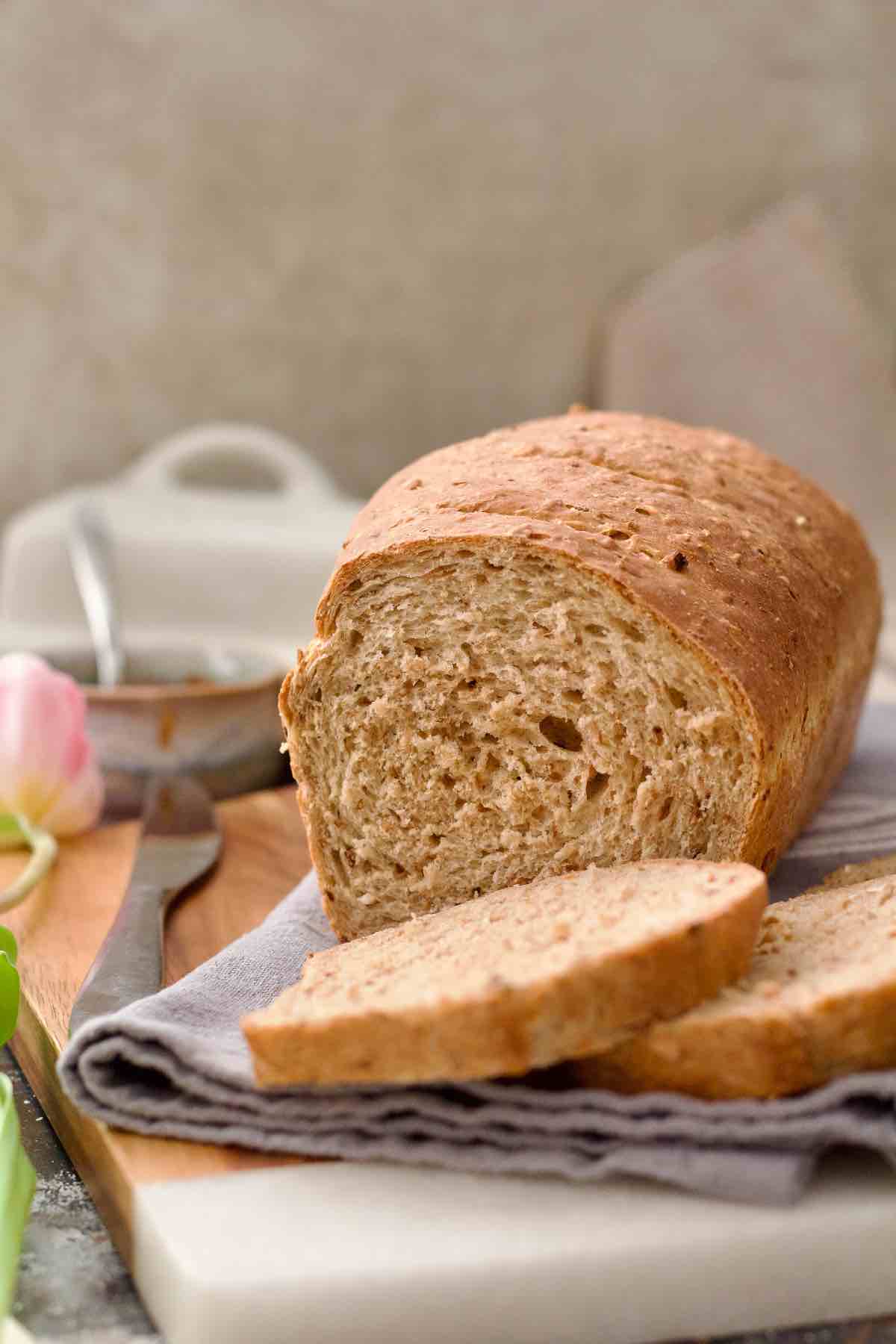 Granary bread loaf with two slices cut in front of it.