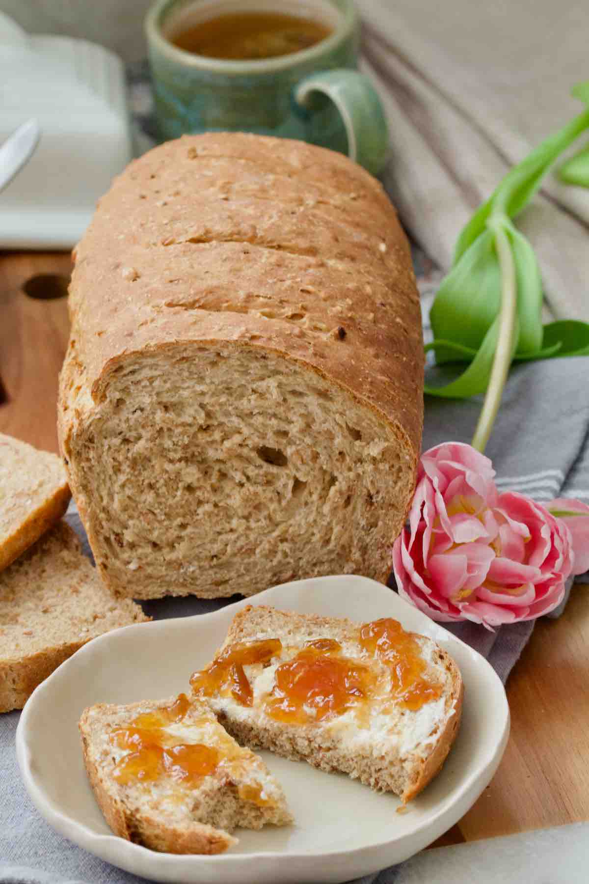 Granary loaf and a slice with butter and jam on a small plate.