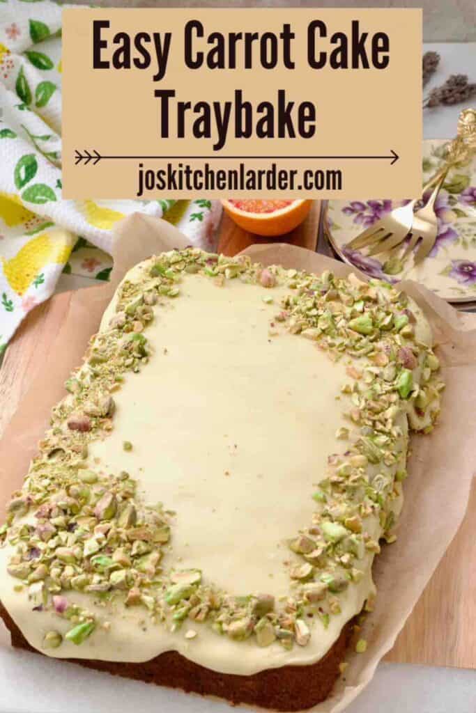 Carrot cake traybake with orange buttercream icing and pistachios on top.