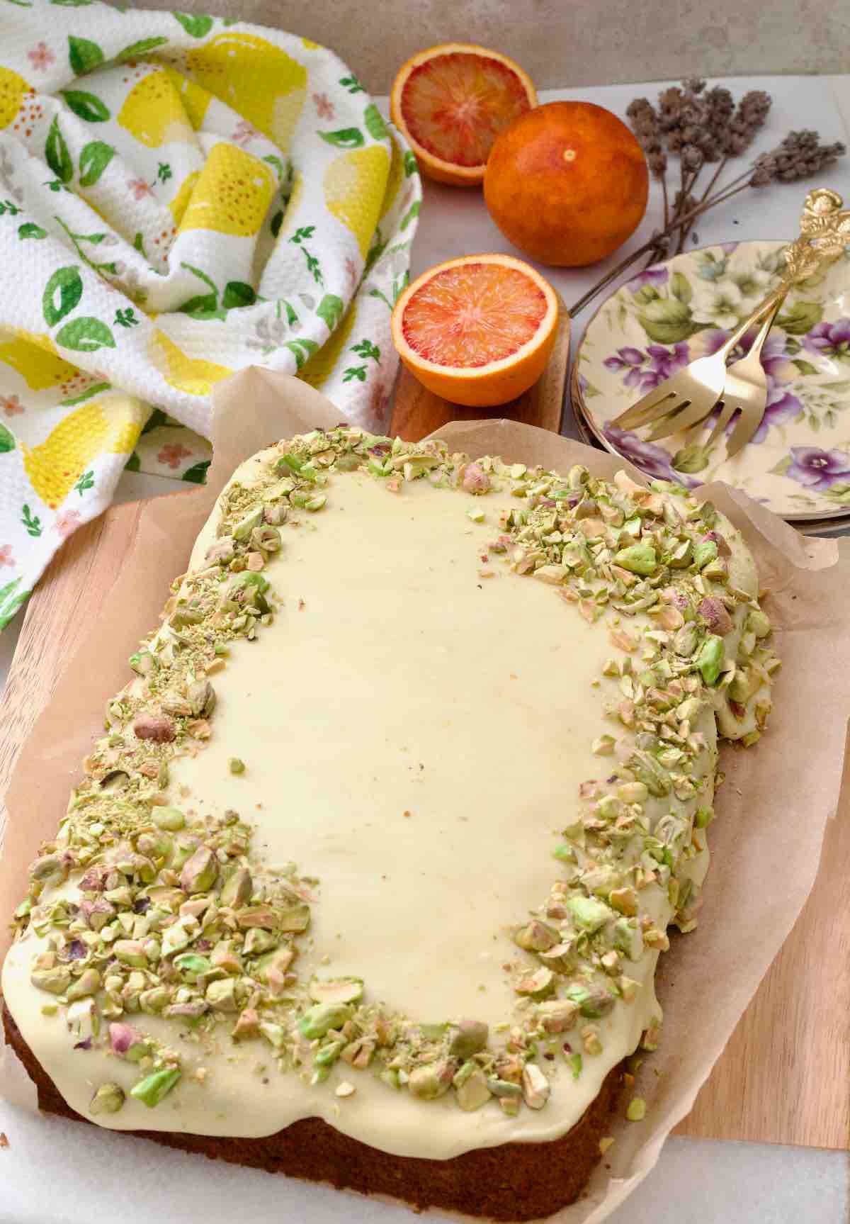 Carrot cake traybake with orange buttercream icing and pistachios on top.