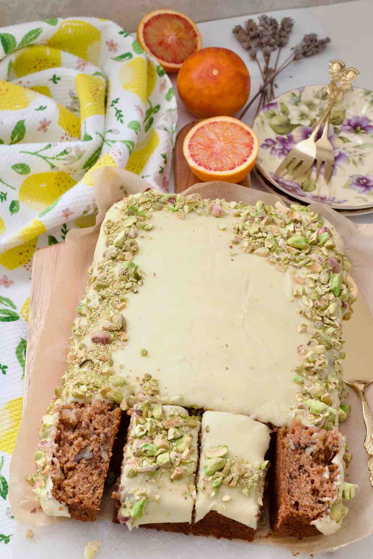 Decorated carrot cake traybake with 4 portions cut, 2 on their sides.