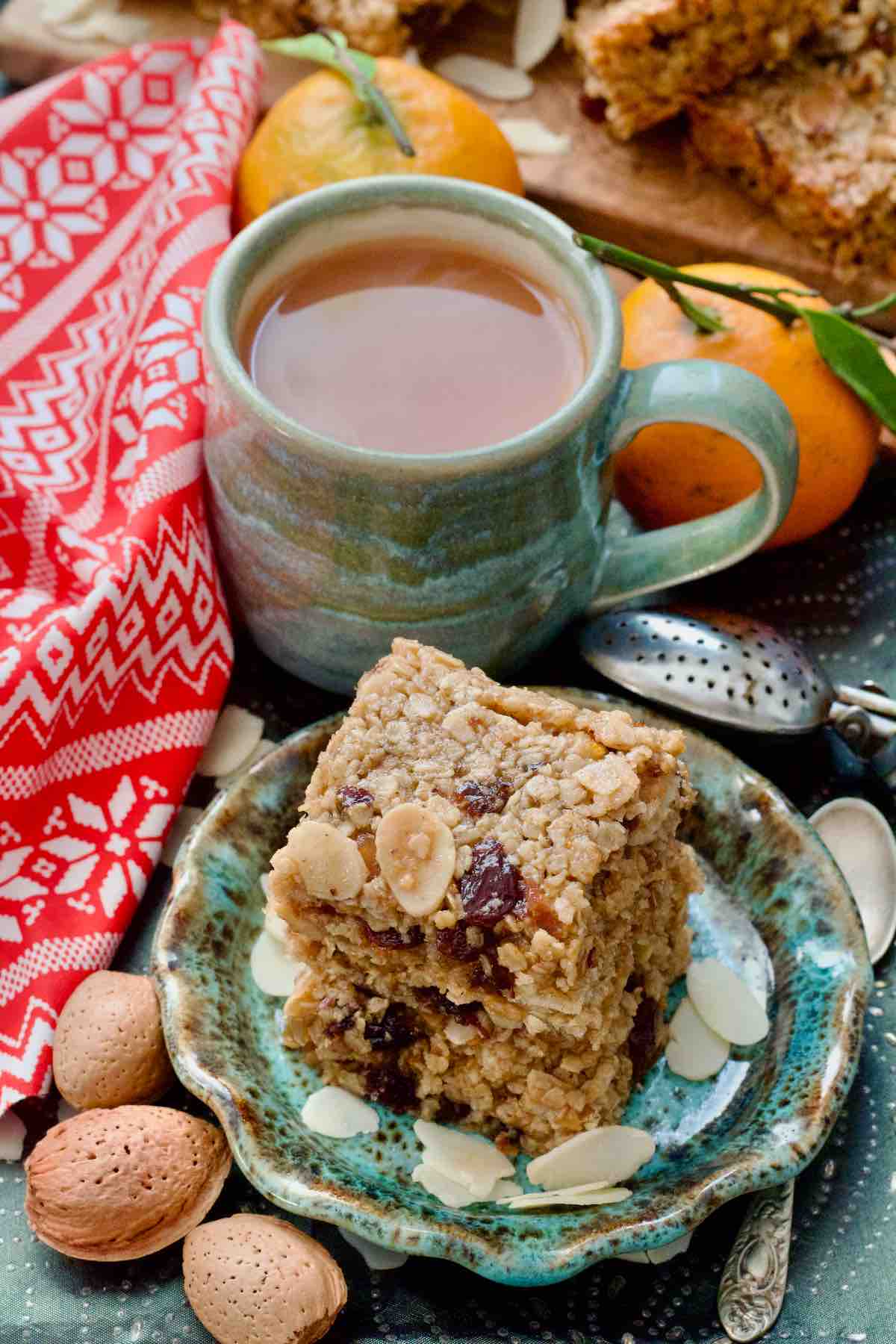 Tower of flapjack squares on a plate, cup with tea behind it.