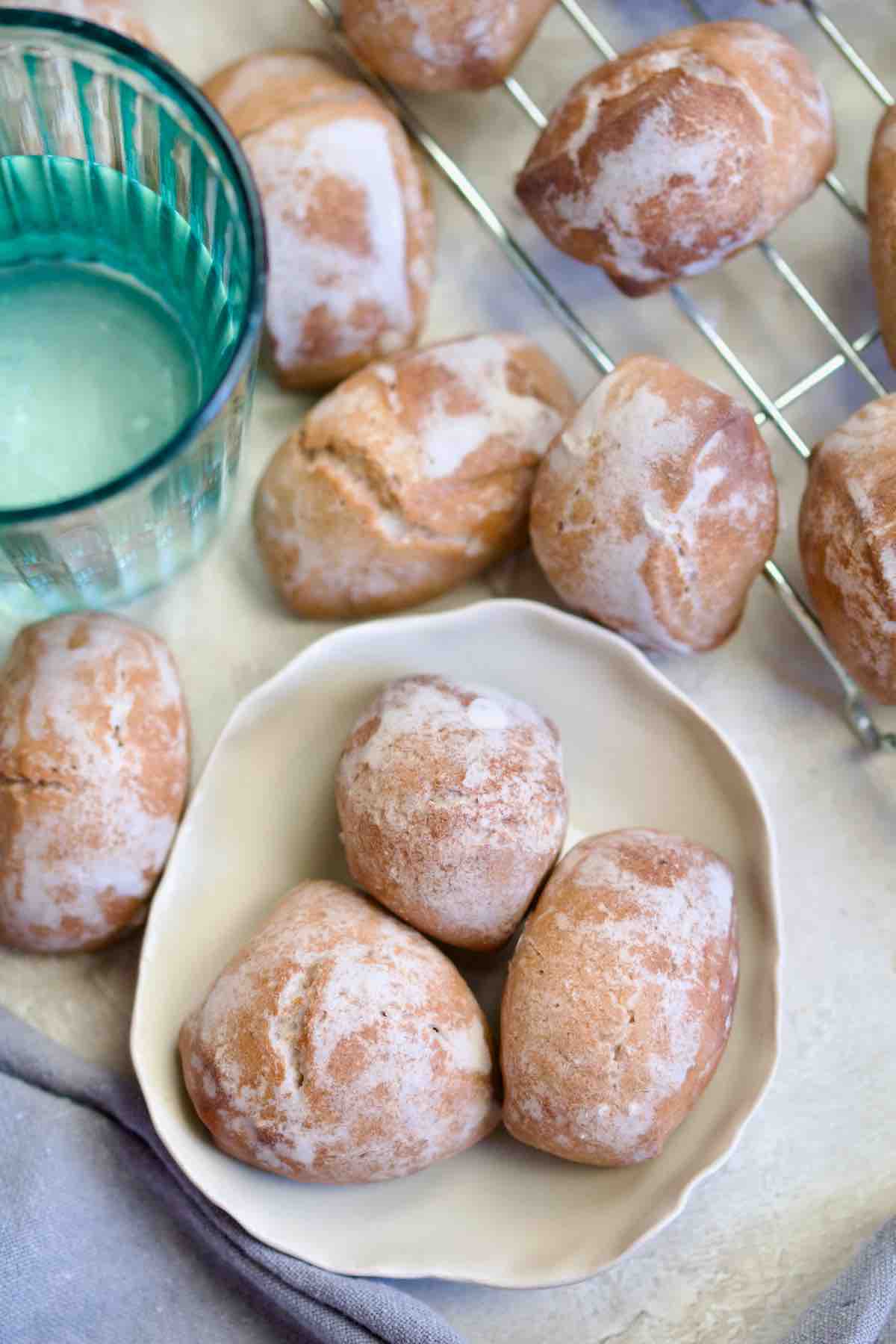 Three pierniczki on a plate, glass of water, more pierniczki around.