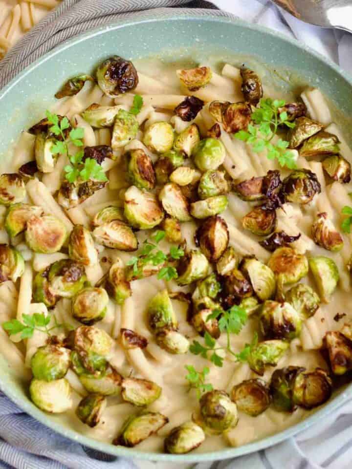 Close up of creamy pasta topped with roasted Brussels sprouts.