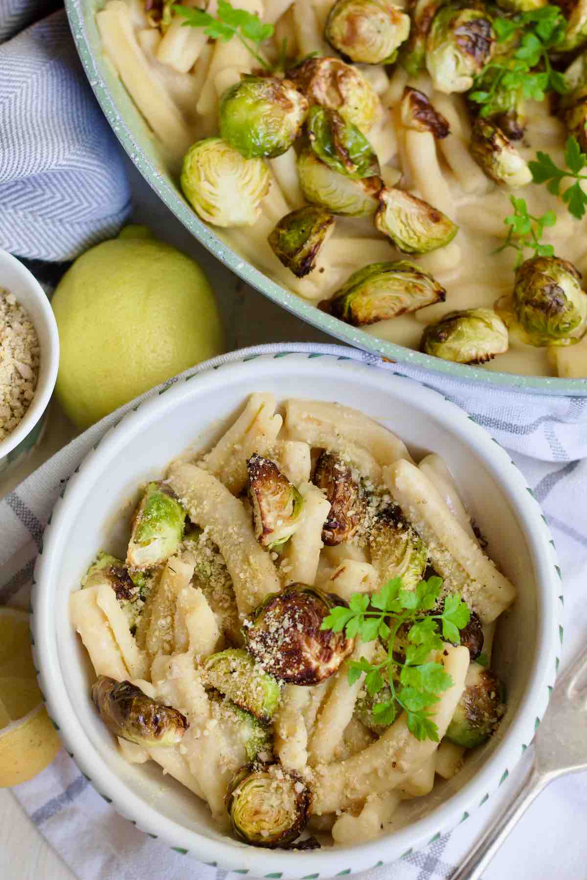 Small bowl filled with creamy pasta with roasted Brussels sprouts and parsley.