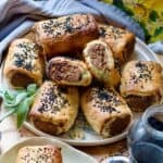 Close up of tofu and mushroom sausage rolls piled up on a plate.