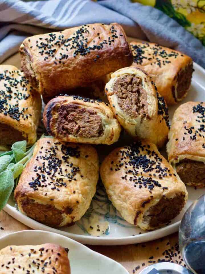 Close up of tofu and mushroom sausage rolls piled up on a plate.