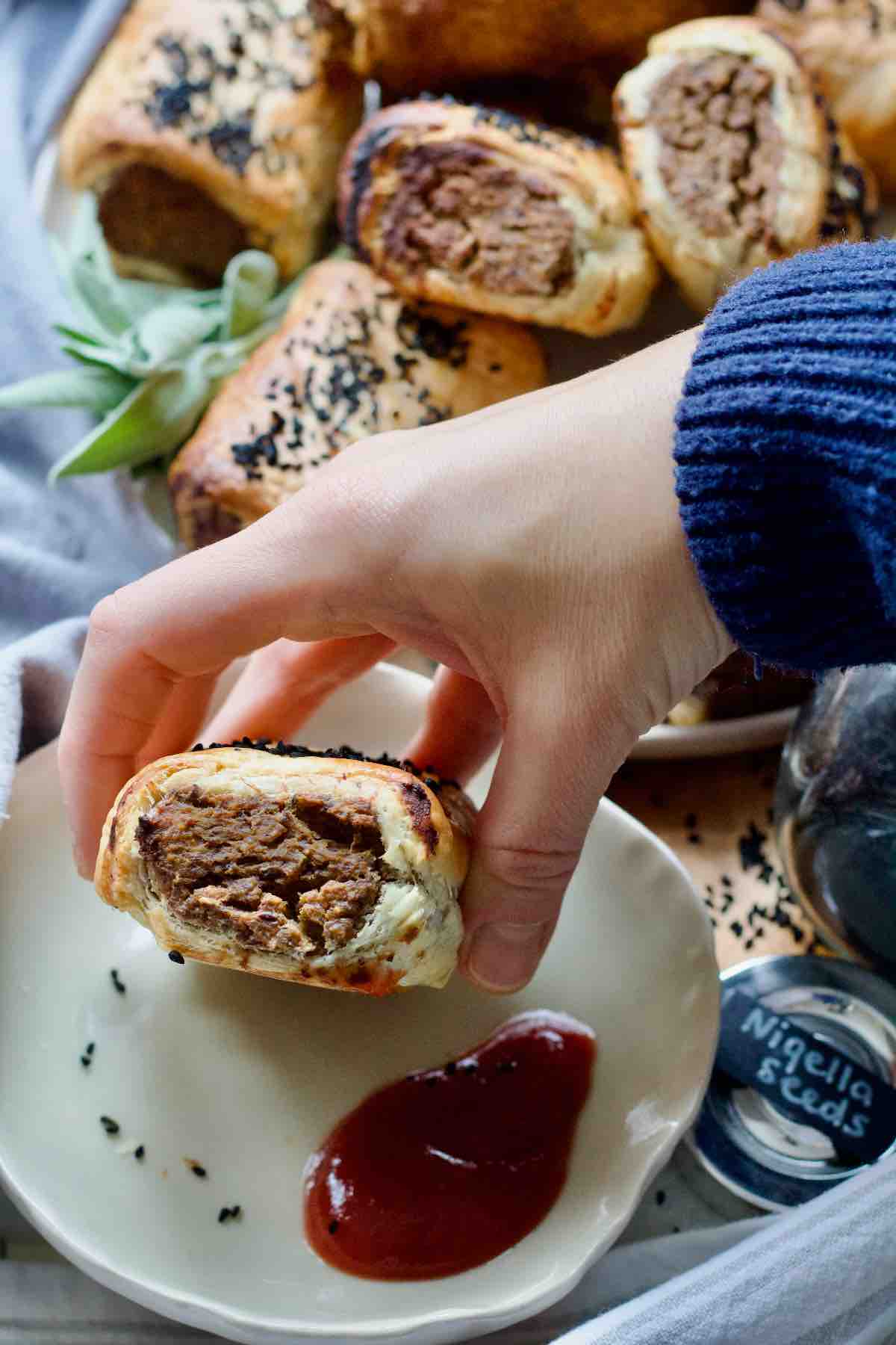 Hand holding sausage roll to show off the filling.