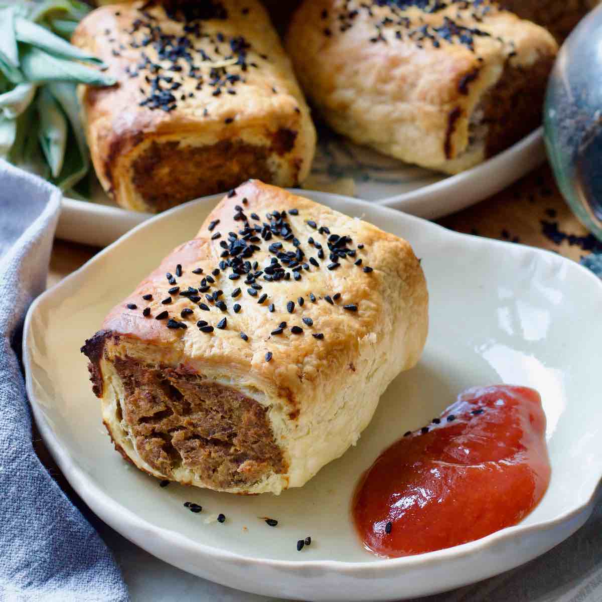 Close up of sausage roll on a plate with a dollop of ketchup.