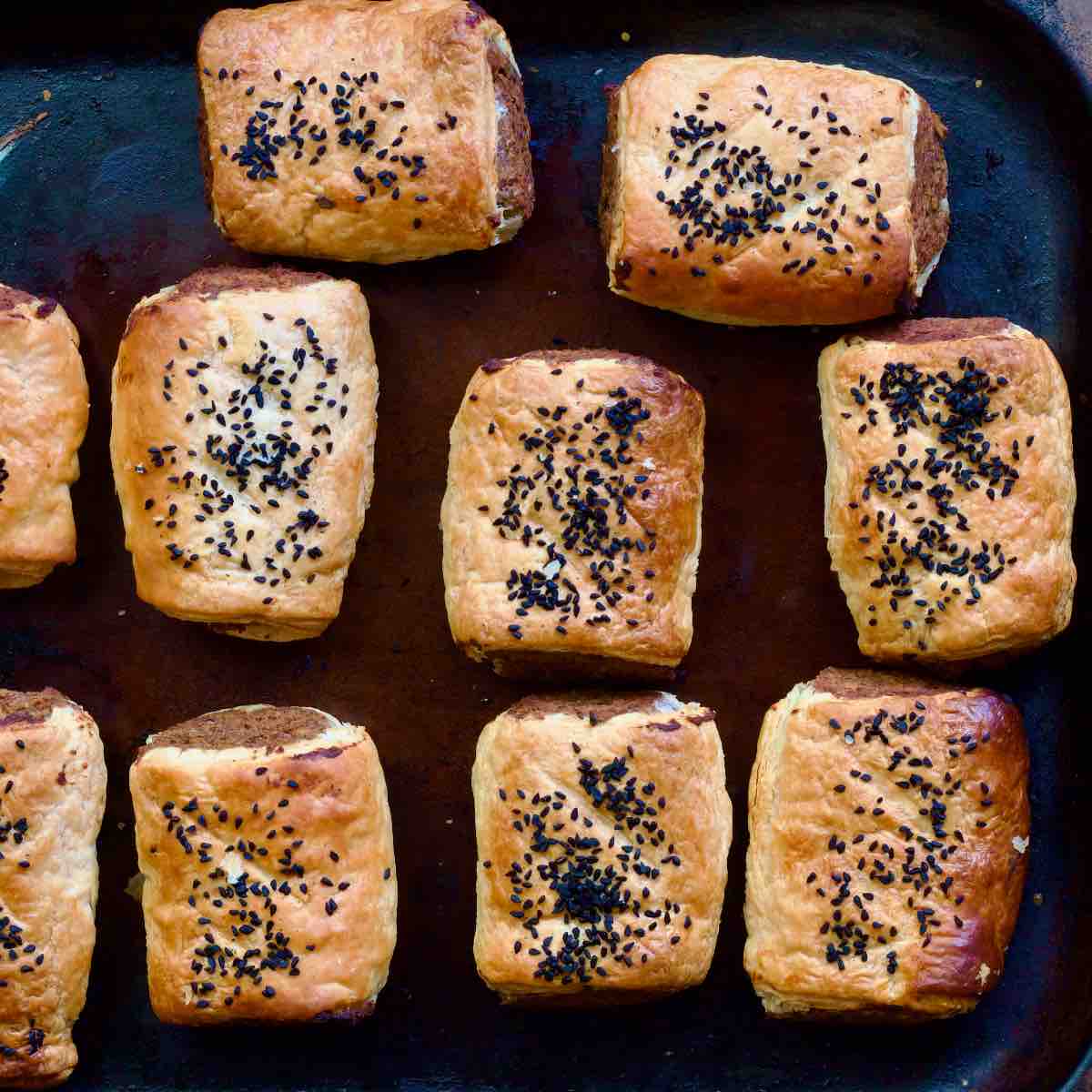 Sausage rolls on a baking tray straight from the oven.