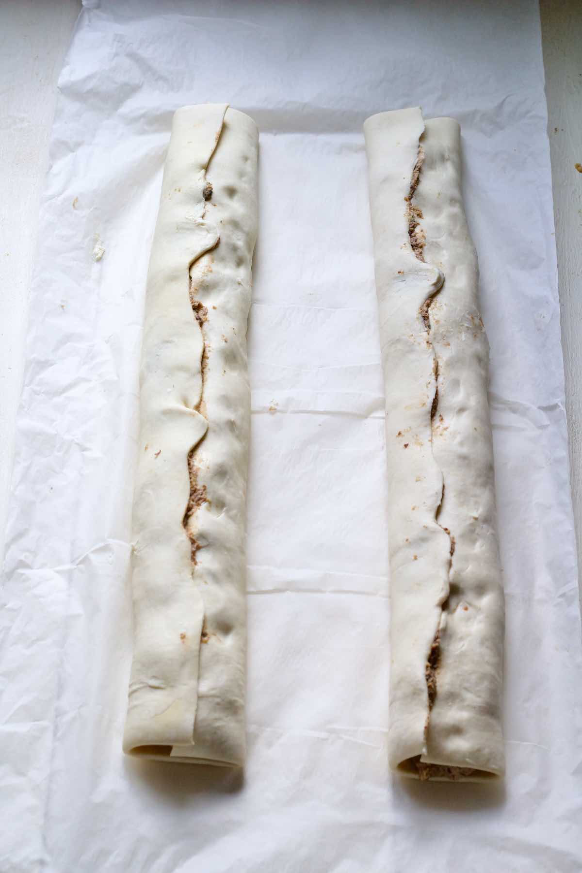 Two long, filled sausage rolls before cutting.