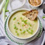 Cauliflower, leek and potato soup in a bowl with a piece of sourdough.