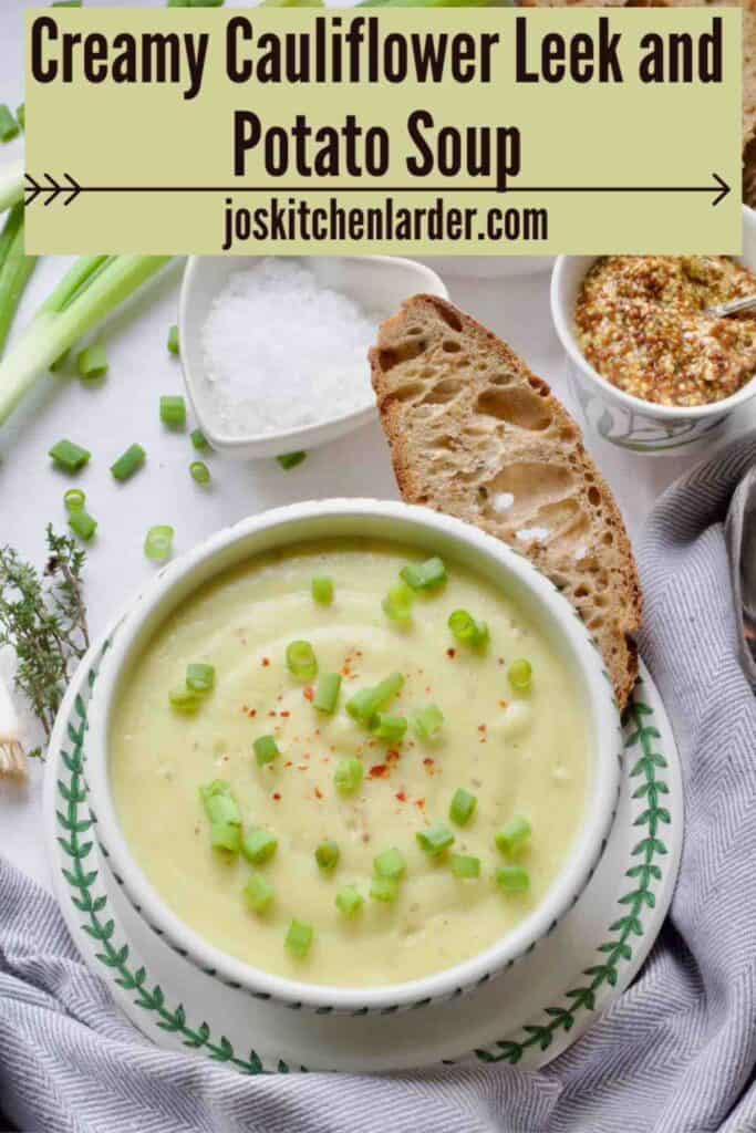 Served portion of garnished cauliflower leek and potato soup in a bowl with bread on a plate.
