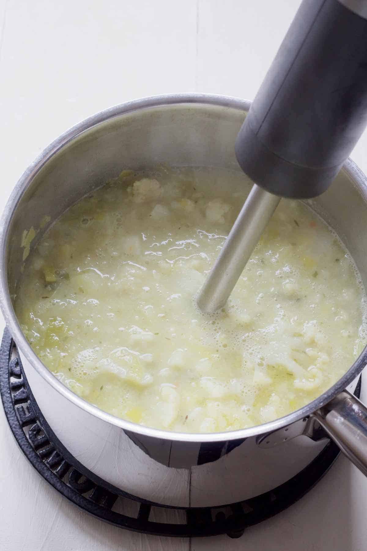 Hand blender blending cooked soup.
