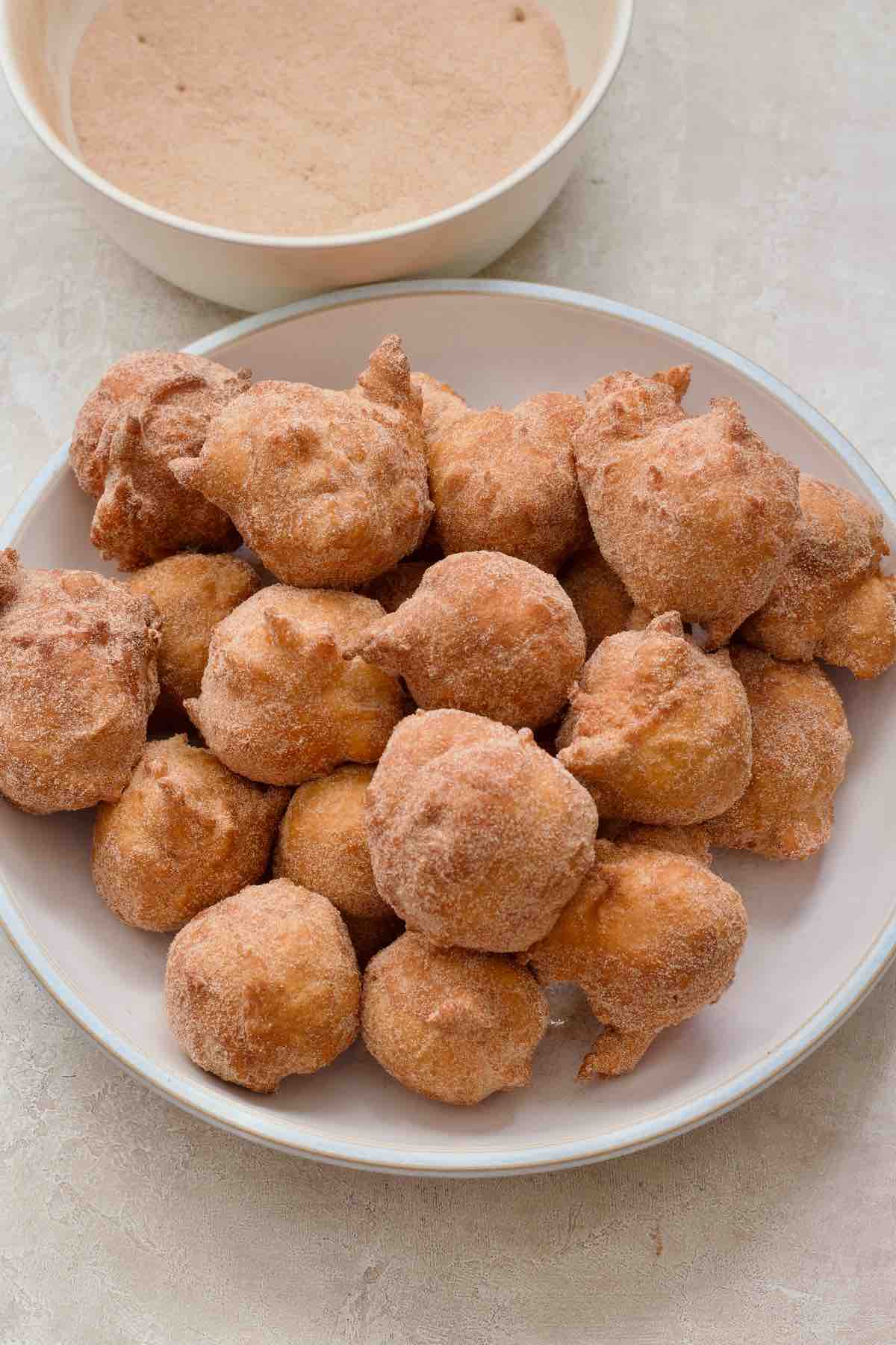 Plate filled with yogurt doughnuts freshly rolled in cinnamon sugar.