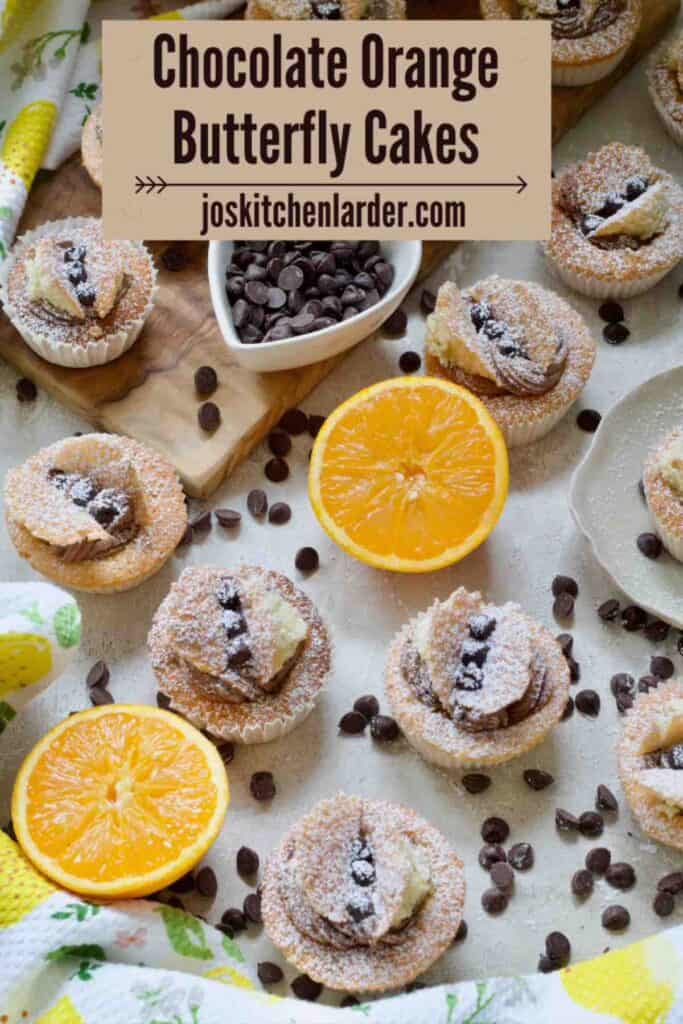 Chocolate orange butterfly cakes with two orange halves and chocolate chips.