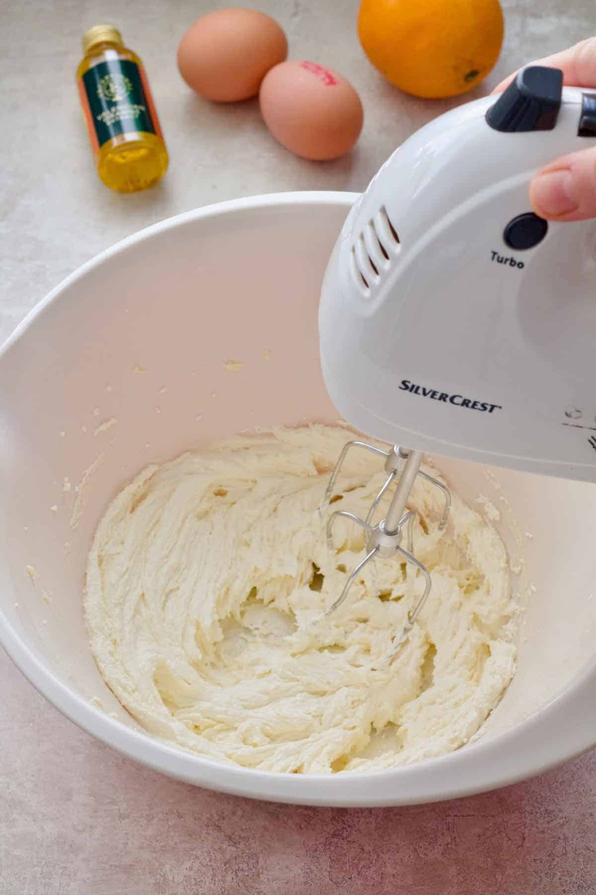 Mixing sugar and butter together with hand mixer.