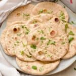 Close up of garlic flatbreads arranged on a plate, sprinkled with fresh parsley.
