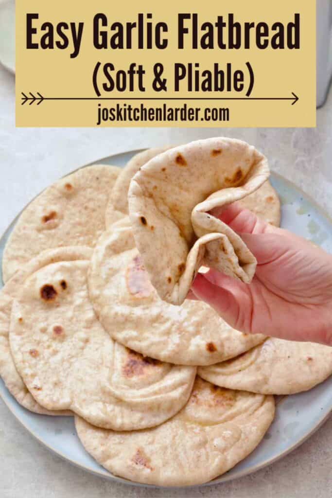 Hand squashing flatbread to show how pliable it is.