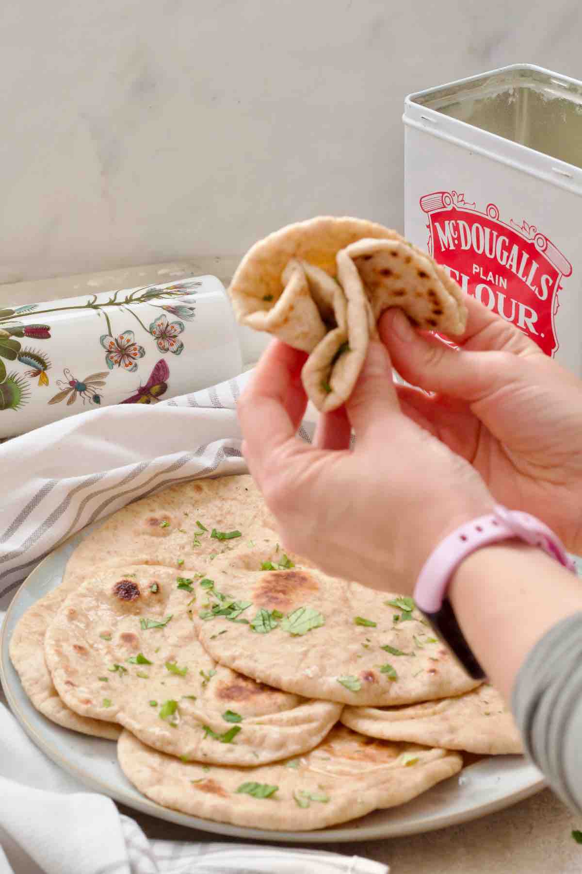 Hands squashing flatbread to show how pliable it is.