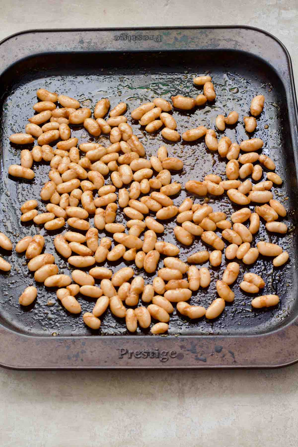Cannellini beans on a baking tray ready to be roasted.