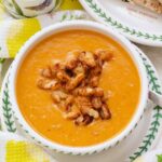 Roasted tomato and sweet potato soup in a bowl with crispy bean garnish.
