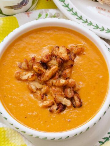 Roasted tomato and sweet potato soup in a bowl with crispy bean garnish.
