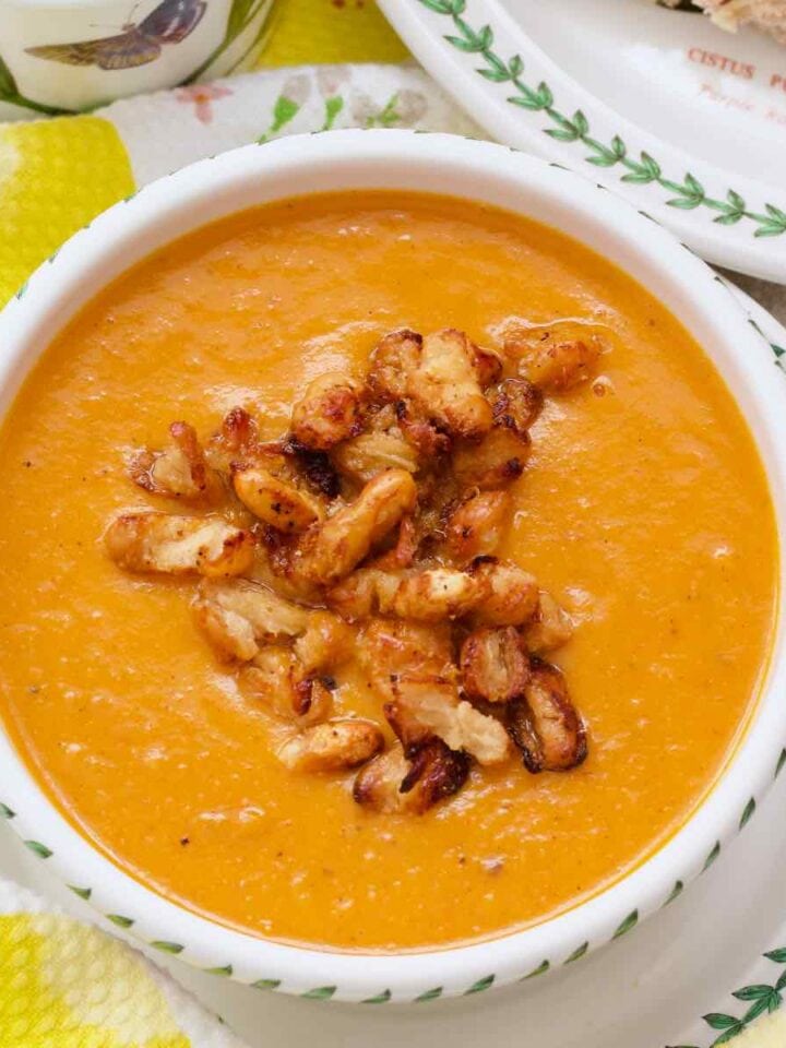 Roasted tomato and sweet potato soup in a bowl with crispy bean garnish.
