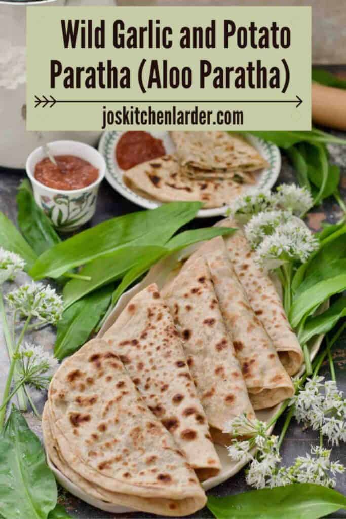 Platter with folded parathas, chutney and served paratha on a plate.
