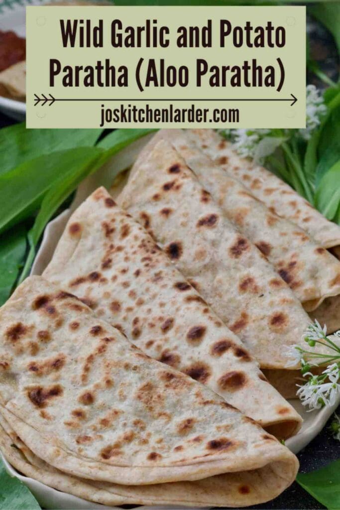 Five folded aloo parathas arranged on a platter with wild garlic.