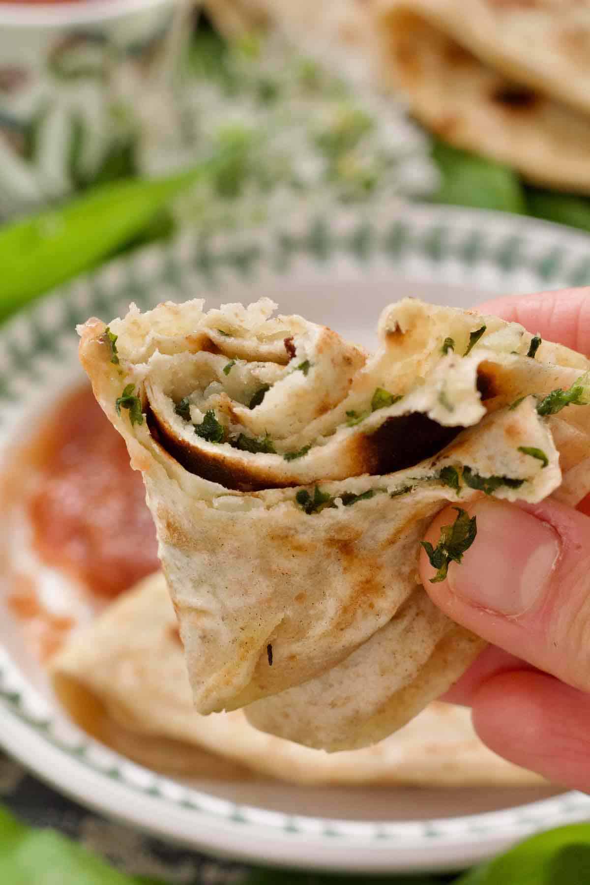 Hand holding paratha, visible wild garlic and potato filling.