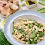 Served broad bean pasta in a bowl, bread and dipping oil behind.