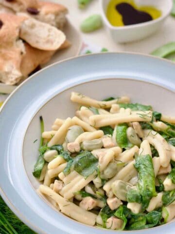 Served broad bean pasta in a bowl, bread and dipping oil behind.
