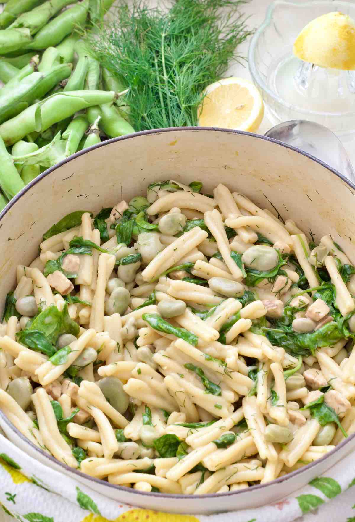 Pot with broad bean pasta, broad bean pods, fresh dill and lemon.