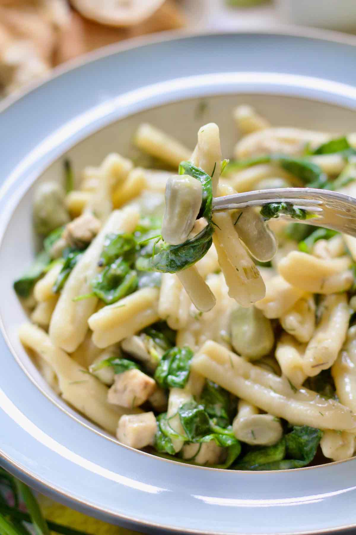 Close up of small bite of broad bean pasta on a fork.