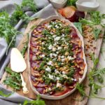 Square photo of beetroot carpaccio with rocket salsa on a platter with serving spoon ready to serve.