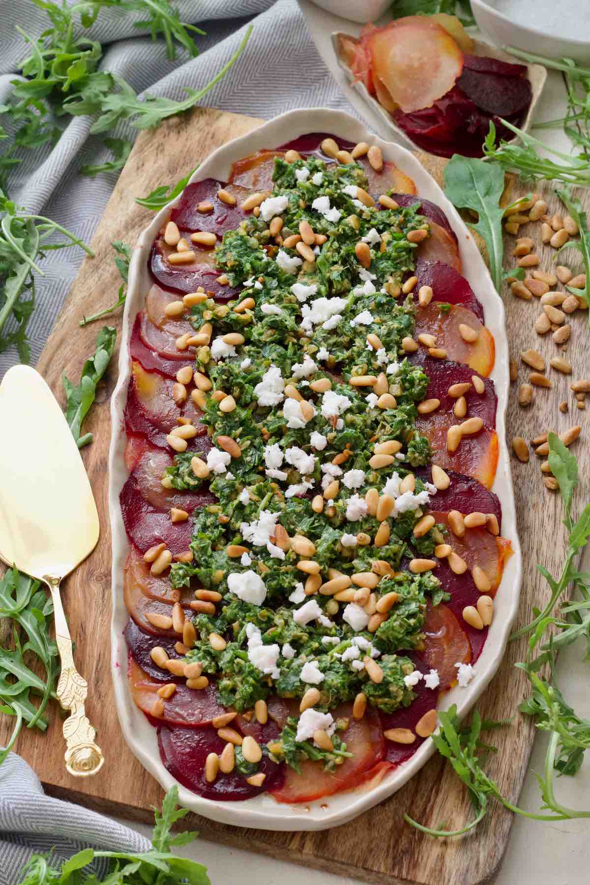 Beetroot carpaccio on a platter with serving spoon on a side.