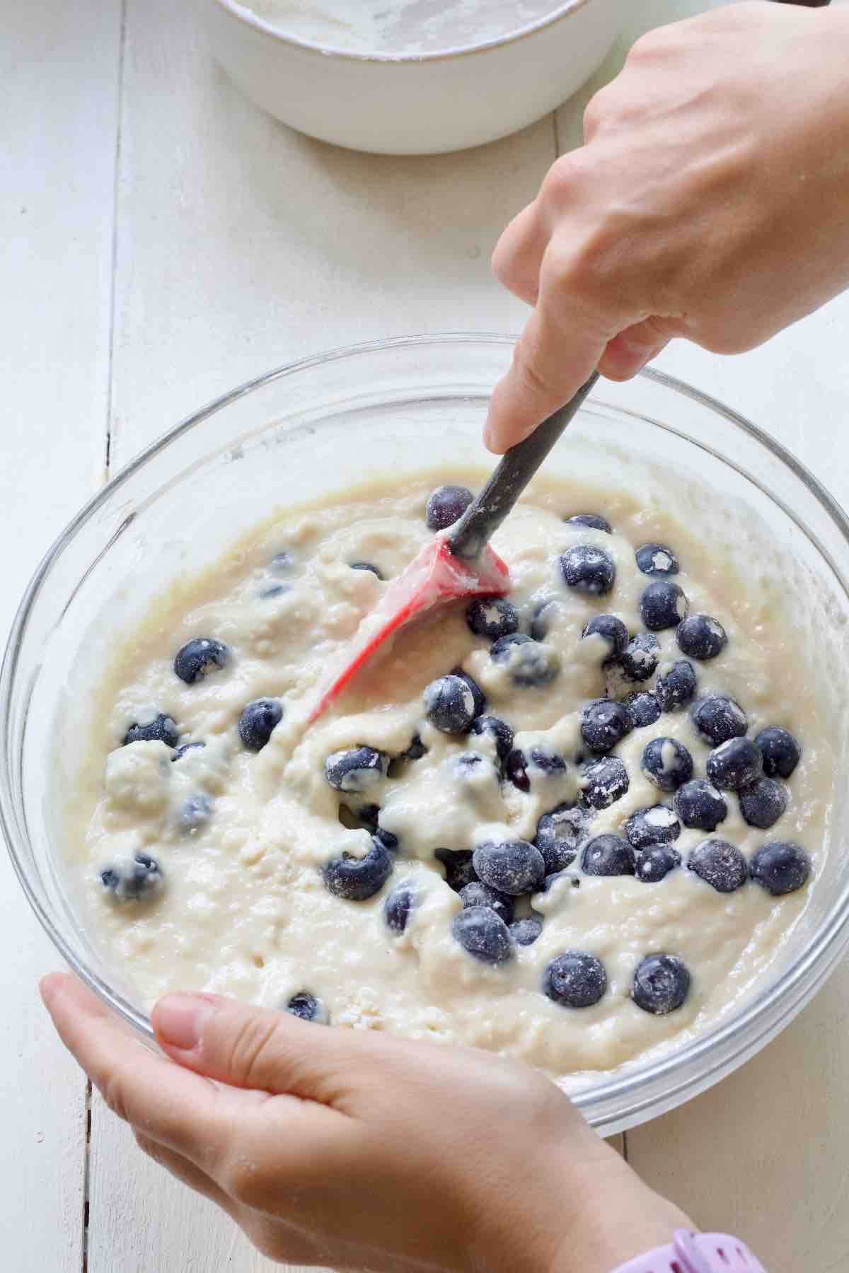 Folding blueberries into cake batter.