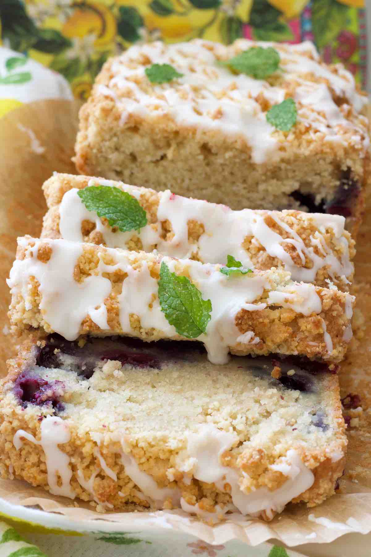 Lemon and blueberry loaf cake partially sliced and garnished with mint.
