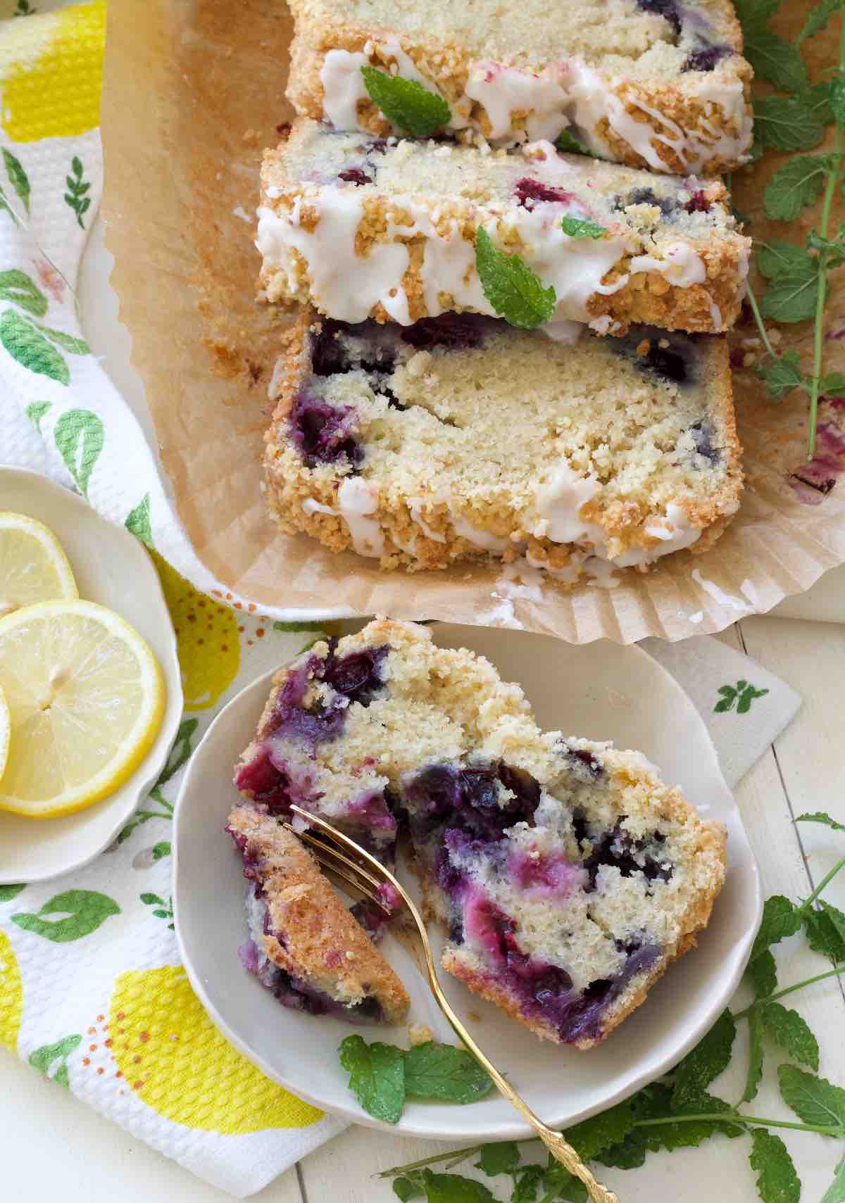Bird view of slice of lemon and blueberry loaf cake on a plate and extra slices.