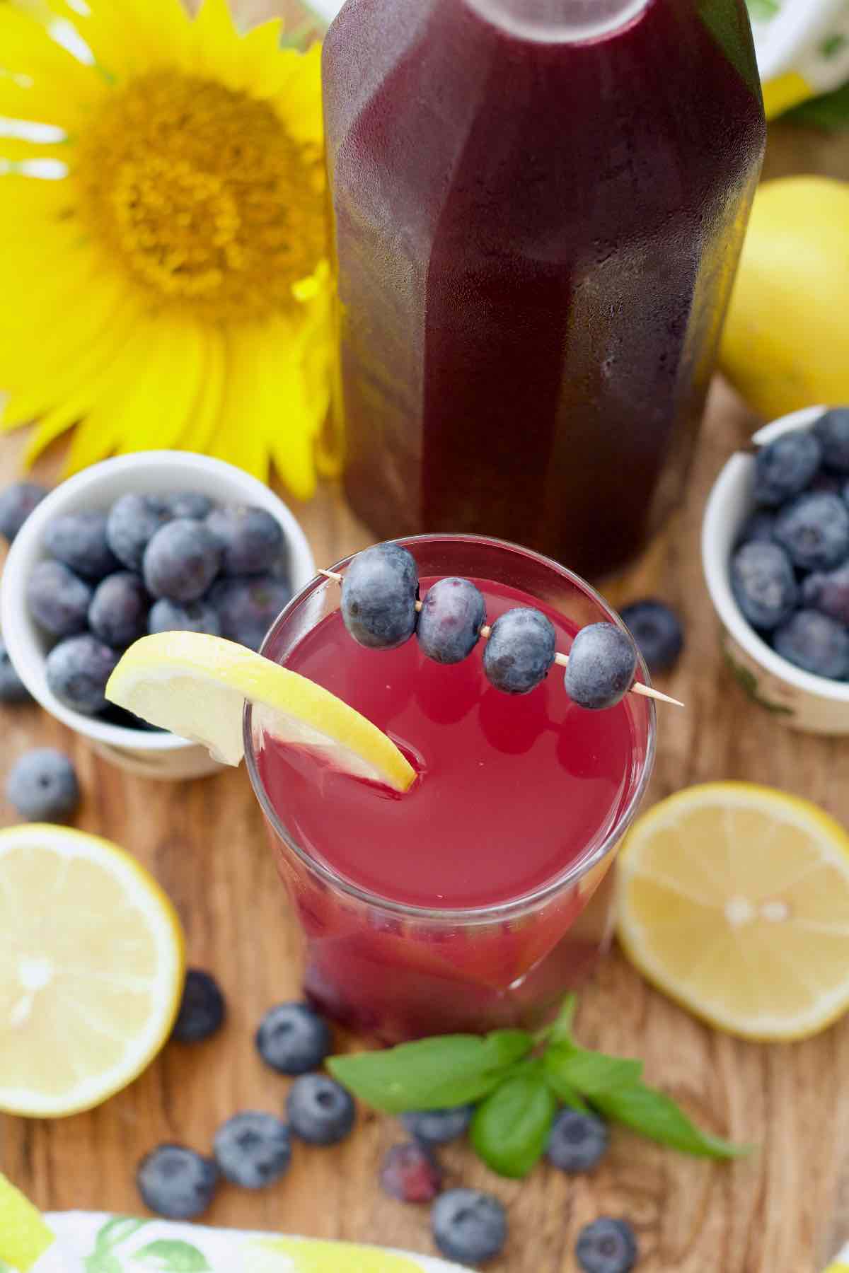 Diluted blueberry syrup drink with its garnishes viewed from the top.