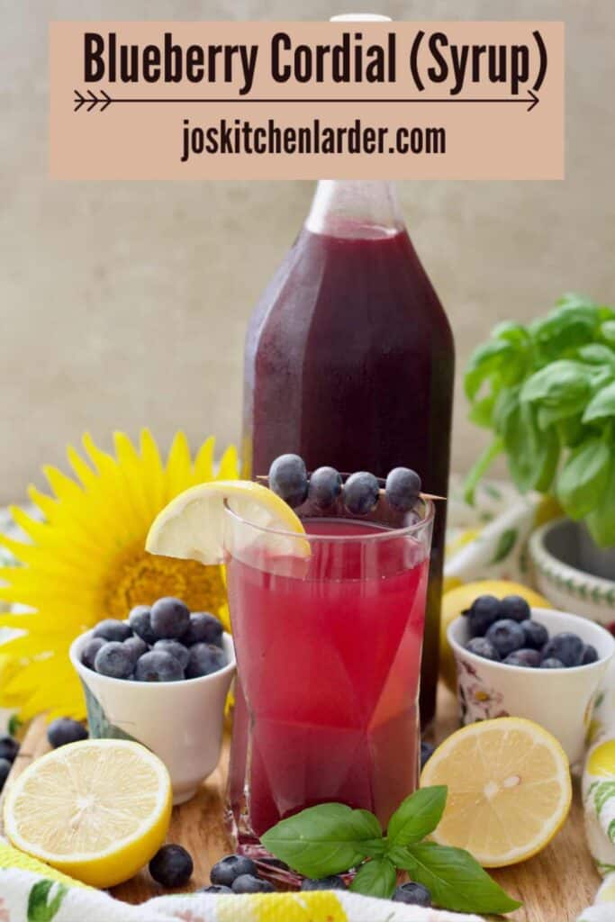 Blueberry syrup in a bottle and some diluted in a glass in front.